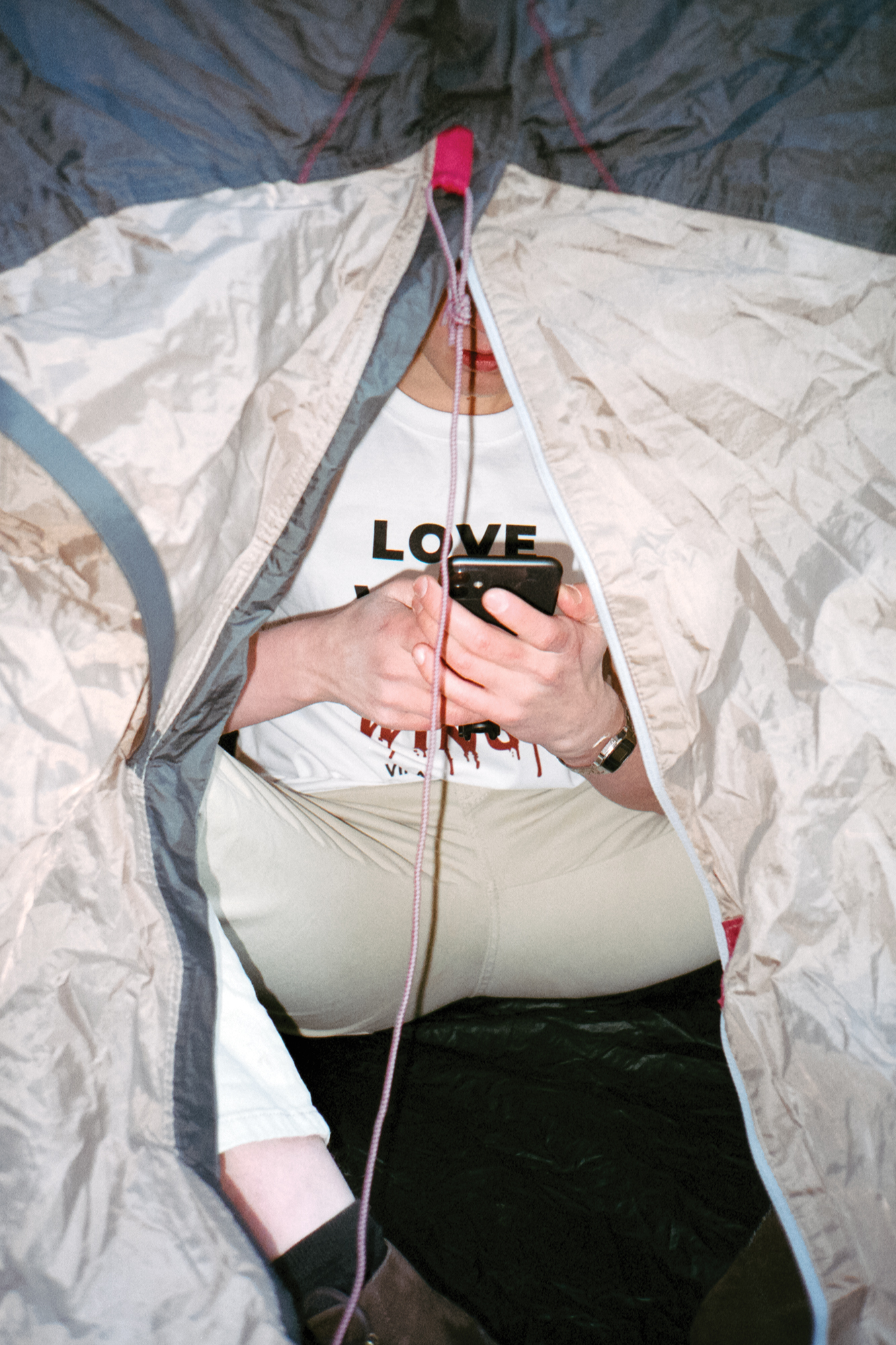 Benjamin Pitkänen istuu teltan sisällä ja selaa puhelintaan.